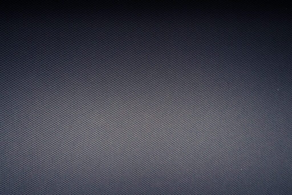 High angle of textured backdrop of carbon fiber textile with shadows on rough gray surface